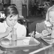 Black and white image of two young girls drinking chocolate milk out of straws